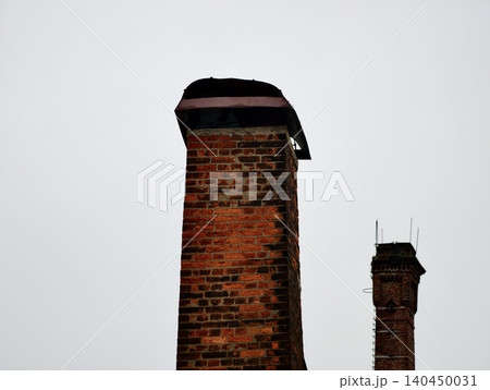 Tall brick chimneys against overcast sky Tall brick chimneys against overcast sky 140450031