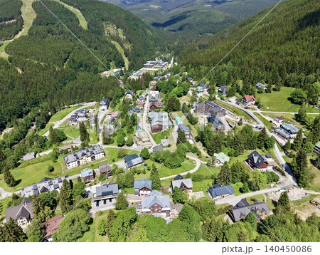 Aerial view of mountain village surrounded by forested slopes 140450086