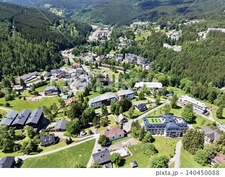 Aerial view of a mountain village with forested hills and clustered buildings Aerial view of a mountain village with forested hills and clustered buildings 140450088