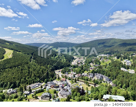 Scenic mountain valley town with forested hills and scattered buildings Scenic mountain valley town with forested hills and scattered buildings 140450089