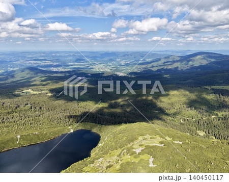 Aerial view of mountain lake and forested ridges under cloudy sky Aerial view of mountain lake and forested ridges under cloudy sky 140450117