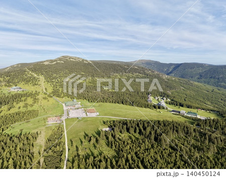Aerial view of mountain resort and forested ridge under blue sky Aerial view of mountain resort and forested ridge under blue sky 140450124