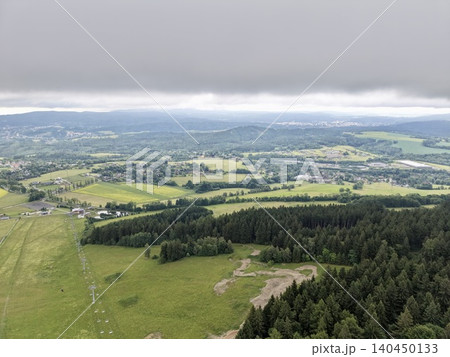 Aerial view of rolling fields, forests and distant hills under a low cloud ceiling Aerial view of rolling fields, forests and distant hills under a low cloud ceiling 140450133