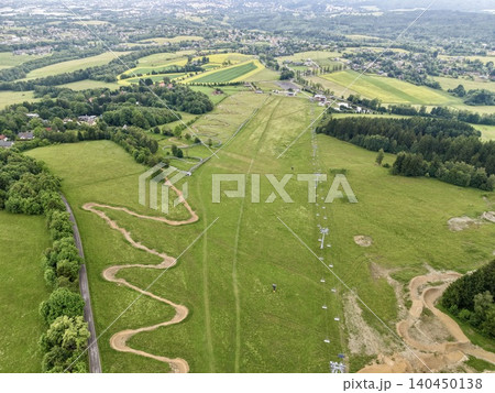 Aerial view of rolling green fields with winding dirt track and rural village Aerial view of rolling green fields with winding dirt track and rural village 140450138