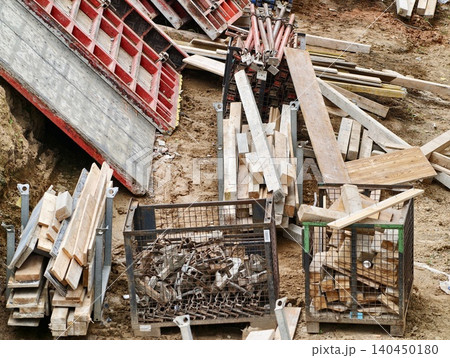 Construction site stacked lumber, metal formwork and hardware in soil Construction site stacked lumber, metal formwork and hardware in soil 140450180