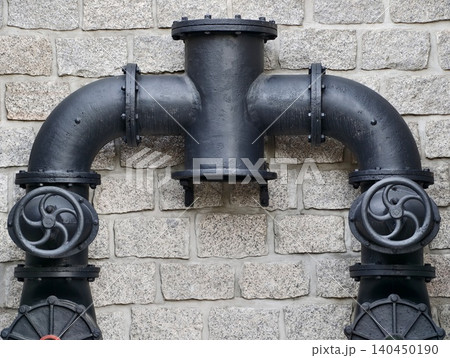 Black cast iron water pipe assembly mounted on stone wall Black cast iron water pipe assembly mounted on stone wall 140450190