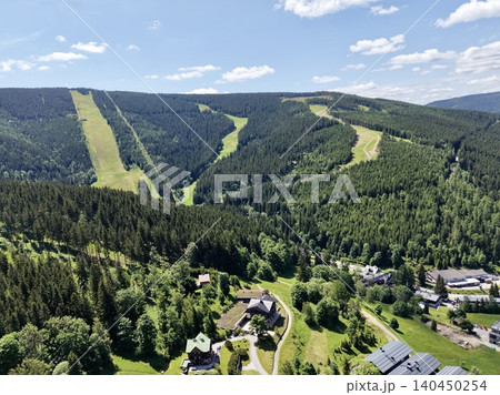 Aerial view of mountain resort with forested slopes and cleared ski runs 140450254