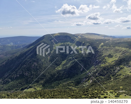 Green mountain ridge and alpine valley under blue sky with scattered clouds 140450270