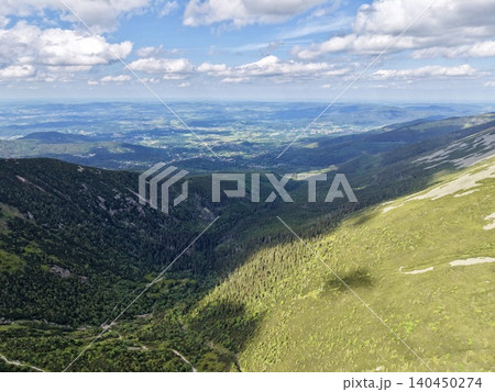 Panoramic mountain ridge with forested valley and distant plains under cloud sky Panoramic mountain ridge with forested valley and distant plains under cloud sky 140450274