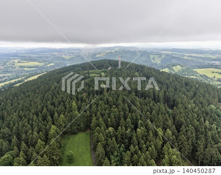 Aerial view of dense conifer forest on rolling hills under cloudy sky Aerial view of dense conifer forest on rolling hills under cloudy sky 140450287