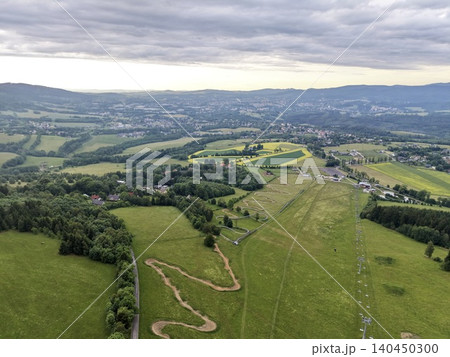 Aerial view of rolling countryside with fields and forest under cloudy sky 140450300