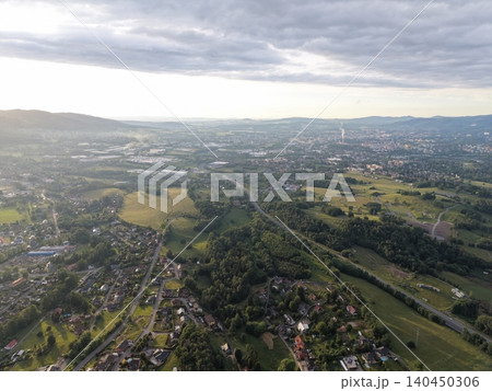 Aerial view of rolling green hills and suburban valley under cloudy sky Aerial view of rolling green hills and suburban valley under cloudy sky 140450306