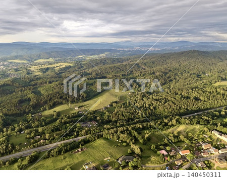 Aerial view of rolling green hills and village under cloudy sky Aerial view of rolling green hills and village under cloudy sky 140450311