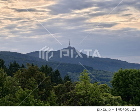 Distant mountain peak with transmission tower above forested ridgelines at dusk 140450322