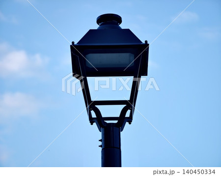 Black street lantern silhouette against blue sky 140450334