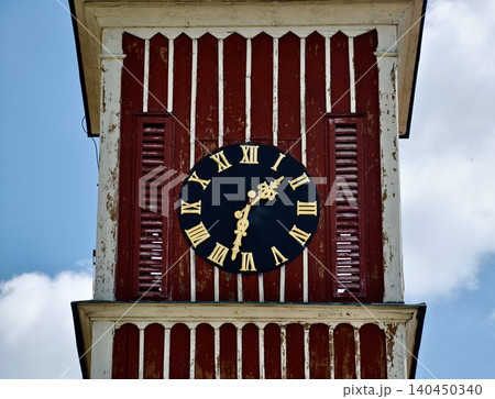Weathered wooden clock tower with Roman numerals against blue sky Weathered wooden clock tower with Roman numerals against blue sky 140450340