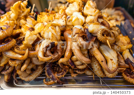 Grilled squid tentacles on metal rack at asian street food market for local culinary business and traditional seafood cuisine concept 140450373