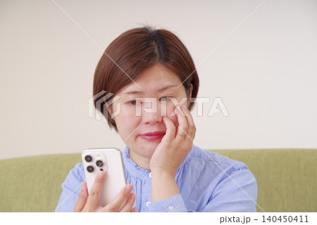 スマホを見て不安そうに考え込む女性 スマホを見て不安そうに考え込む女性 140450411