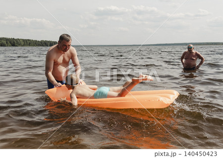 father son enjoying relaxing summer day, floating inflatable mattress calm river. man holding child securely ensuring safety while both enjoy water. Outdoor recreation, family vacation, summer nature father son enjoying relaxing summer day, floating inflatable mattress calm river. man holding child securely ensuring safety while both enjoy water. Outdoor recreation, family vacation, summer nature 140450423