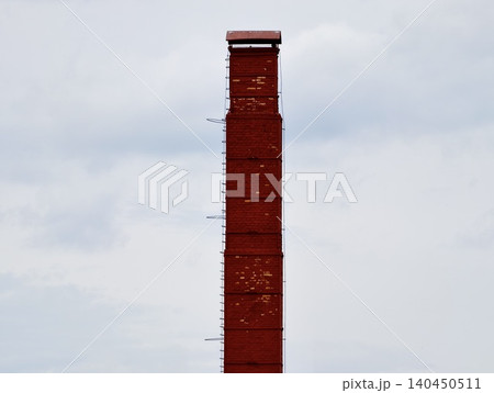 Red industrial chimney against a cloudy sky Red industrial chimney against a cloudy sky 140450511