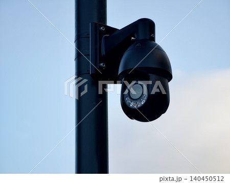 Security camera mounted on a pole against a clear sky 140450512