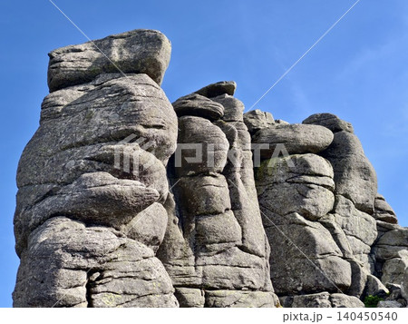 Weathered granite rock formations rising against a clear blue sky 140450540