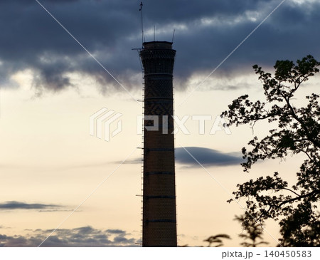 Tall industrial chimney against a dramatic cloudy sky Tall industrial chimney against a dramatic cloudy sky 140450583