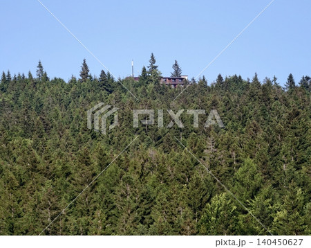 Wooded hillside with a lone cabin and antenna peeking above evergreen trees Wooded hillside with a lone cabin and antenna peeking above evergreen trees 140450627