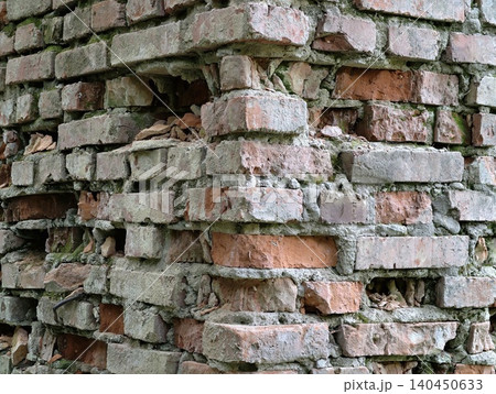 Weathered brick wall corner with crumbling mortar and plant debris Weathered brick wall corner with crumbling mortar and plant debris 140450633