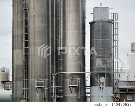 Industrial stainless steel storage silos with ladders and piping Industrial stainless steel storage silos with ladders and piping 140450658