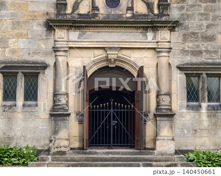 Stone building entrance with arched doorway and metal gate Stone building entrance with arched doorway and metal gate 140450661