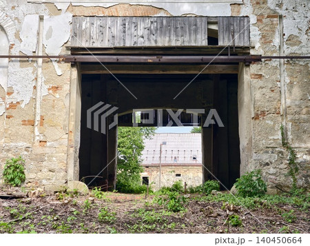 Arched entry through weathered stone and timber barn to inner courtyard 140450664