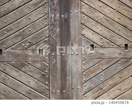 Weathered wooden gate with diagonal planks and iron studs 140450678