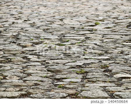 Weathered cobblestone street with grass 140450684