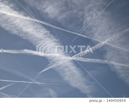 Contrails And Clouds In Open Blue Sky. Crisscrossed Vapor Streaks Under Expansive Daytime Sky Atmosphere Contrails And Clouds In Open Blue Sky. Crisscrossed Vapor Streaks Under Expansive Daytime Sky Atmosphere 140450954
