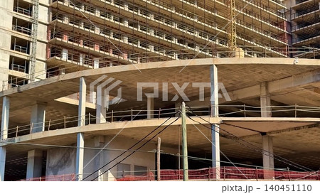 A busy construction site featuring cranes, a building structure, and various materials A busy construction site featuring cranes, a building structure, and various materials 140451110