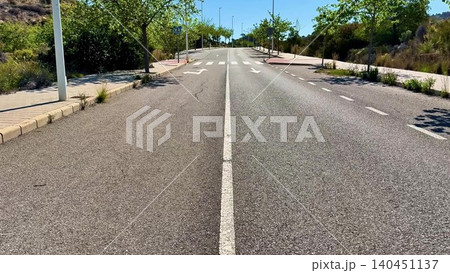 A Scenic View of an Abandoned Road Surrounded by Lush Greenery and a Bright Blue Sky 140451137