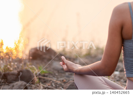Close-up of a woman's hand in meditation mudra during outdoor yoga at sunset, showing mindful breathing, inner balance, calm focus, spiritual wellness, peaceful nature, and warm copy space. Close-up of a woman's hand in meditation mudra during outdoor yoga at sunset, showing mindful breathing, inner balance, calm focus, spiritual wellness, peaceful nature, and warm copy space. 140452665