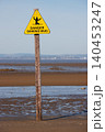 Bright yellow sinking mud warning sign on beach 140453247