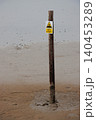 Danger sinking mud sign on pole in beach sand at low tide 140453289