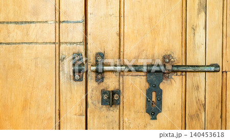 Rustic antique brass door bolt on wooden door panel 140453618