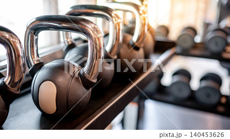 Set of kettlebells and dumbbells lined up on metal gym rack Set of kettlebells and dumbbells lined up on metal gym rack 140453626