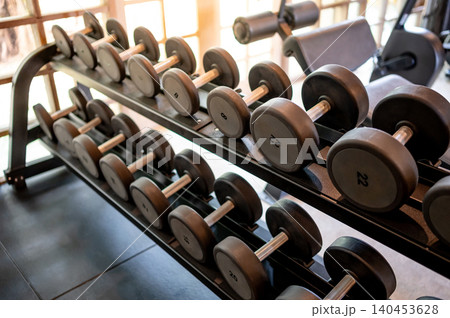 Set of dumbbells lined up by size on metal gym rack Set of dumbbells lined up by size on metal gym rack 140453628