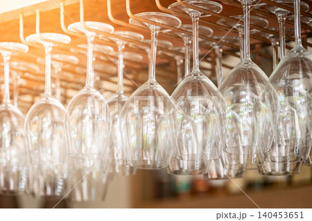 Empty wine glasses hang upside down on the rack over bar counter 140453651