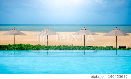 Luxury swimming pool with beach umbrella and sea landscape ahead 140453652