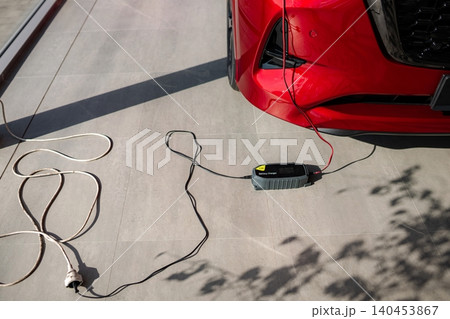 Red car battery charger connected recharging power Red car battery charger connected recharging power 140453867