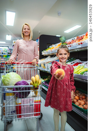 Mother and daughter buying fresh fruit in grocery store Mother and daughter buying fresh fruit in grocery store 140453929