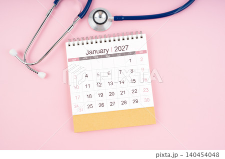 January 2027 desk calendar and Medical stethoscope on pink background. January 2027 desk calendar and Medical stethoscope on pink background. 140454048