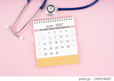 June 2027 desk calendar and Medical stethoscope on pink background. June 2027 desk calendar and Medical stethoscope on pink background. 140454067