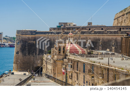 Historic limestone fortifications and bastion walls of Valletta Malta with red domed church and harbour view under clear blue sky. High quality photo Historic limestone fortifications and bastion walls of Valletta Malta with red domed church and harbour view under clear blue sky. High quality photo 140454145